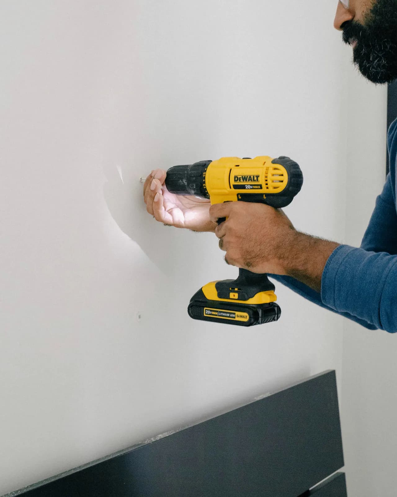 Handyman drilling into a wall to mount a fixture