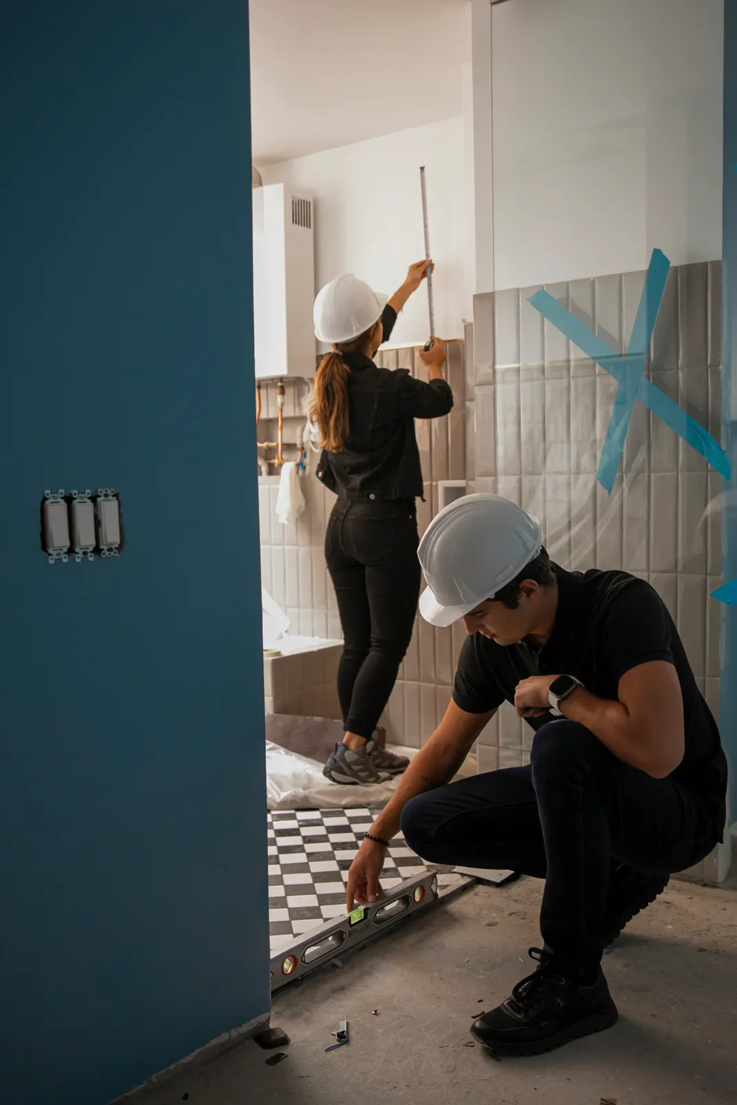 Two tradespeople measuring and tiling a bathroom